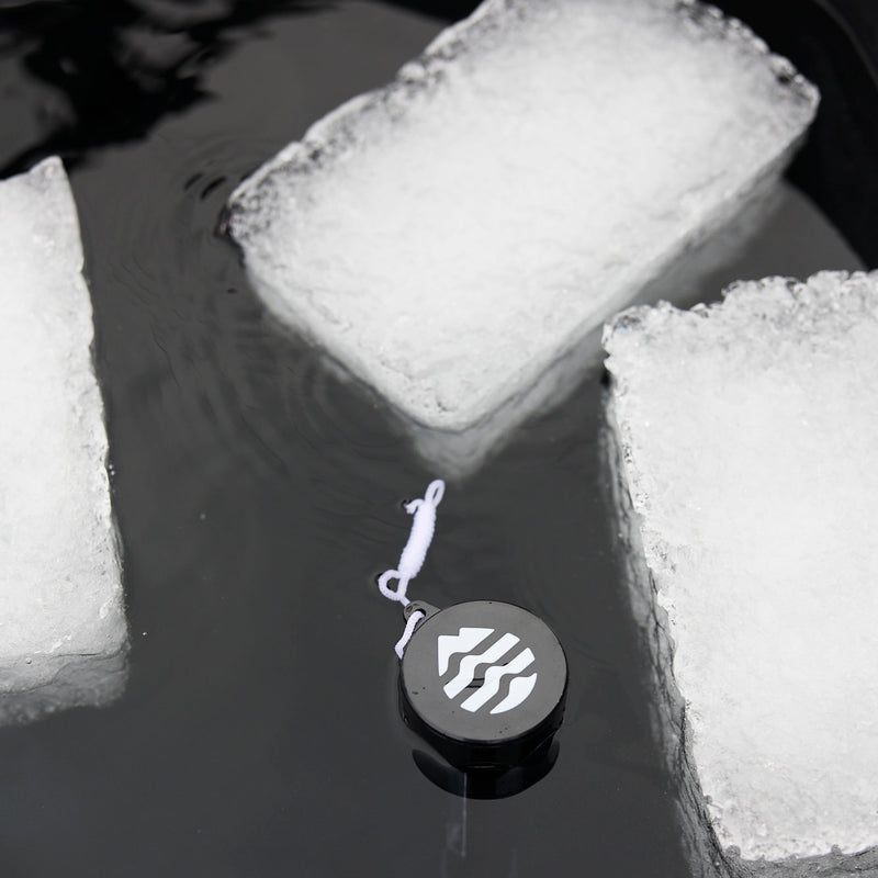 three big ice blocks floating in a cold tub along with the ice barrel thermometer